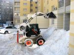 Бобкат сбрасывает снег на клумбы